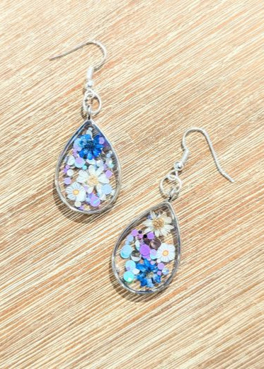 Oorbellen met droogbloemen, fantasiebloemen en blauwe glitterconfetti in epoxy